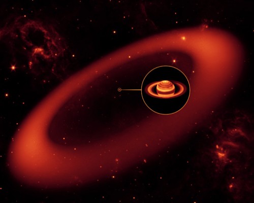 This artist's conception shows a nearly invisible ring around Saturn -- the largest of the giant planet's many rings. It was discovered by NASA's Spitzer Space Telescope.  The artist's conception simulates an infrared view of the giant ring. Saturn appears as just a small dot from outside the band of ice and dust. The bulk of the ring material starts about six million kilometers (3.7 million miles) away from the planet and extends outward roughly another 12 million kilometers (7.4 million miles). The ring's diameter is equivalent to roughly 300 Saturns lined up side to side.  The inset shows an enlarged image of Saturn, as seen by the W.M. Keck Observatory at Mauna Kea, Hawaii, in infrared light. The ring, stars and wispy clouds are an artist's representation. 